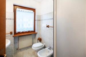 a bathroom with a toilet and a sink and a window at Residence Malibu Appartamento 9 in Falcade +16 photos