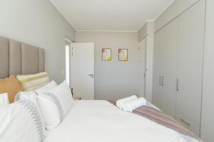 a white bedroom with a large bed with white pillows at Casa Bella in Summerstrand +25 photos