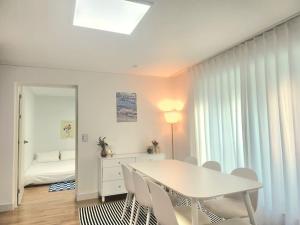 a white dining room with a white table and chairs at Raon Seoul in Seoul