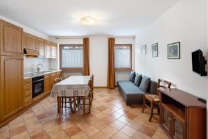 a kitchen and living room with a table and a couch at Residence Malibu Appartamento 8 in Falcade