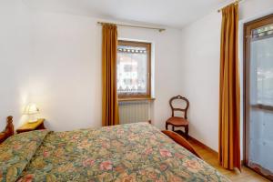 a bedroom with a bed and a window and a chair at Residence Malibu Appartamento 5 in Falcade