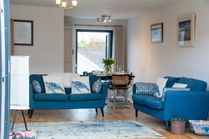 a living room with two blue chairs and a table at 113 Cae Du in Abersoch