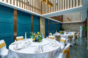 a dining room with white tables and chairs and flowers at Imperial Traders Elong Hotel in Guangzhou