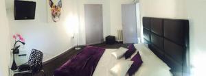 a bedroom with a bed with a purple blanket on it at Hôtel Le Capitole in Toulouse