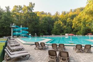 a large swimming pool with chairs and a slide at Hotel Toplice - Terme Krka in Smarjeske Toplice