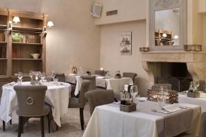 a restaurant with white tables and chairs and a fireplace at Le Mas De La Rose - Teritoria in Orgon