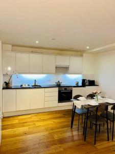 クロイドンにあるLuxury Flat in London, Croydonの白いキャビネットとテーブルと椅子のあるキッチン