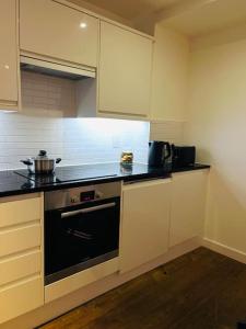 クロイドンにあるLuxury Flat in London, Croydonのキッチン(白いキャビネット、黒いコンロ付)