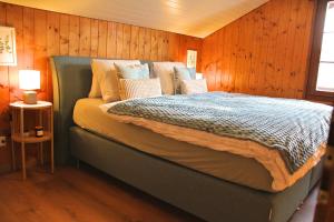 a bed in a room with a wooden wall at Am See l 15 Minuten nach Interlaken l gratis Parking in Faulensee