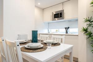 a white kitchen with a table with plates and glasses at Apartamento Golden Naimara in Cabanas de Tavira