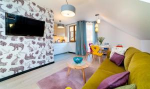 a living room with a couch and a tv on a wall at Apartamenty EverySky Nadrzeczna 3E-3D in Karpacz