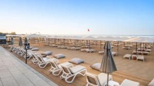 a row of lounge chairs and umbrellas on a deck at Miramare Queen Hotel - Ultra All Inclusive in Side