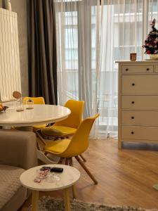 a living room with a table and yellow chairs at D&E Apart in Bucharest