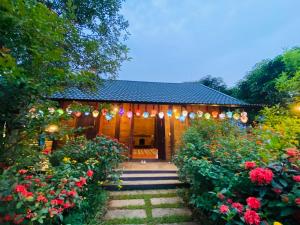 a house with a garden with flowers and lights at La Vie En Rose Ba Vì Homestay in Hanoi