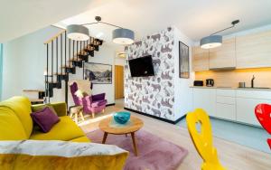 a living room with a yellow couch and colorful chairs at Apartamenty EverySky Nadrzeczna 3E-3D in Karpacz