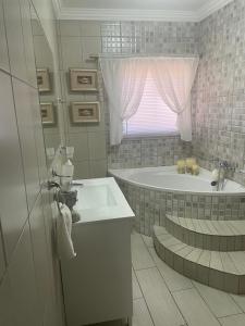 a white bathroom with a tub and a sink at Krantz-Aloe guesthouse in Winterkamp