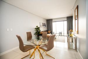 a dining room with a glass table and chairs at One Hyde Park Apartments Sandton in Johannesburg