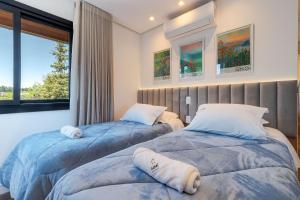 two beds in a room with a window at Aconchego a 500m Rua Coberta by Achei Gramado in Gramado