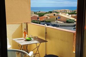 a table with wine glasses on a balcony at Appartement Saint Pierre la Mer 5 personnes, vue sur la mer, piscine, parking, tennis C164 in Saint Pierre La Mer