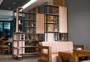 a library with a pink couch and wooden shelves at Oxygen Boutique Hotel in Tirana