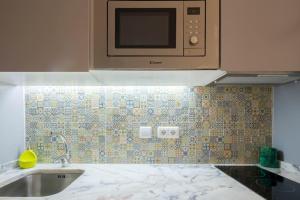 a kitchen with a sink and a microwave at Almada Music in Porto +4 photos