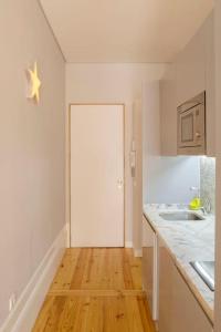 a white kitchen with a white door and a wooden floor at Almada Music in Porto