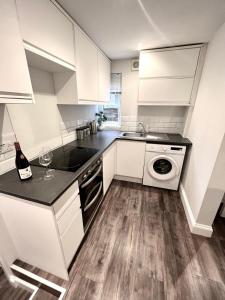 a kitchen with white cabinets and a sink and a dishwasher at Central Stay in Watford