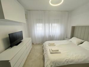 a white bedroom with a bed and a flat screen tv at Nubia Modern Apartment in Craiova