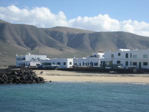 a group of white buildings on a beach with mountains at Absolute Beachfront Apartment in Famara