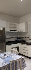 eine Küche mit weißen Schränken und einem Tisch darin in der Unterkunft Apartamento em Penha in Penha