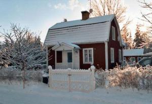 a small house with a white fence in the snow at Villa Lilla Pärla in Virserum