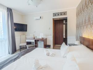 a bedroom with a white bed with a desk and a computer at Holiday Beach Budapest Wellness Hotel with Sauna Park in Budapest