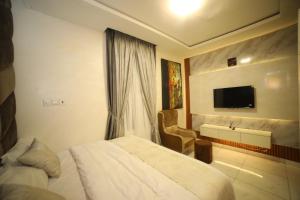 una camera d'albergo con un letto e una televisione di Damac a Ikuata