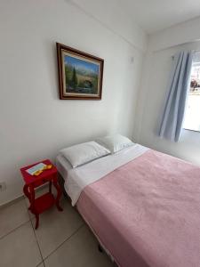 1 dormitorio con cama y mesa roja en Apê 101 5 min praia Abricó Rio das Ostras 2 quartos 4 pessoas com área externa com churrasqueira e rede, en Rio das Ostras