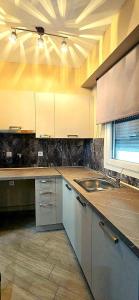 a kitchen with white cabinets and a sink at Gpxclr MicroLuxeSuite in Larisa