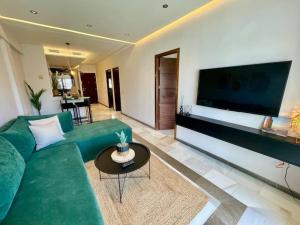 丹吉尔Natural Harmony Suite - 2 BR Marina Bay Beach View的客厅配有绿色沙发和大屏幕平面电视