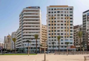 丹吉尔Natural Harmony Suite - 2 BR Marina Bay Beach View的两座高大的建筑,有棕榈树