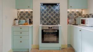 a kitchen with blue cabinets and a stove at Chequers Cottage in Coberley