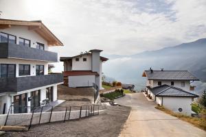 a winding road between two houses with mountains in the background at Apart Mountainview in Rohrberg