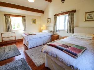 a bedroom with two beds and two windows at Heron Cottage in Shrewsbury