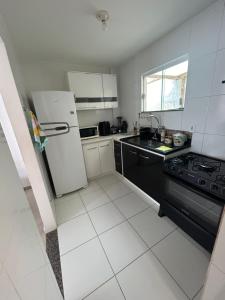 una cocina con refrigerador y estufa en Apê 101 5 min praia Abricó Rio das Ostras 2 quartos 4 pessoas com área externa com churrasqueira e rede, en Rio das Ostras