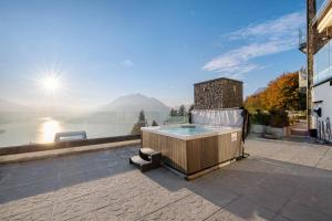 un patio con bañera de hidromasaje y vistas al agua en Summer and Winter, en Perledo