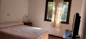 ein Schlafzimmer mit einem Bett, einem Fernseher und einem Fenster in der Unterkunft Cabaña LAS PALMAS dos dormitorios in Santa Clara del Mar