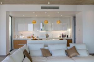 a living room with a white couch and a kitchen at Magic Cave Villa in Tinos in Agios Sostis