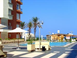 uma piscina com cadeiras e guarda-sóis ao lado de um edifício em Le Monte Carlo em Sousse