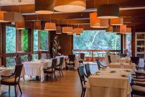a restaurant with white tables and chairs and large windows at Mariva Dune Suites in San Vincenzo