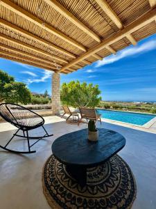 a patio with a table and chairs and a pool at Villa Giorgianna -near Aliki beach with pool in Aliki