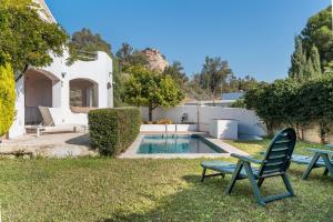 a yard with a pool and two lawn chairs at Apartamentos Villa Martinez in Salobreña