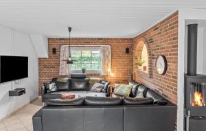 a living room with a couch and a brick wall at Nice Home In Væggerløse With Sauna in Marielyst
