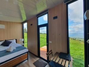 a bedroom with a bed and a balcony with a view at Aorangi Peak Cabins 5 by Tiny Away in Rotorua